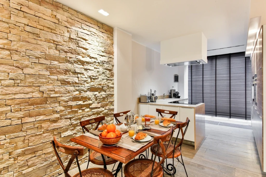 Stylish dining area with natural stone accent wall and modern kitchen setup. 