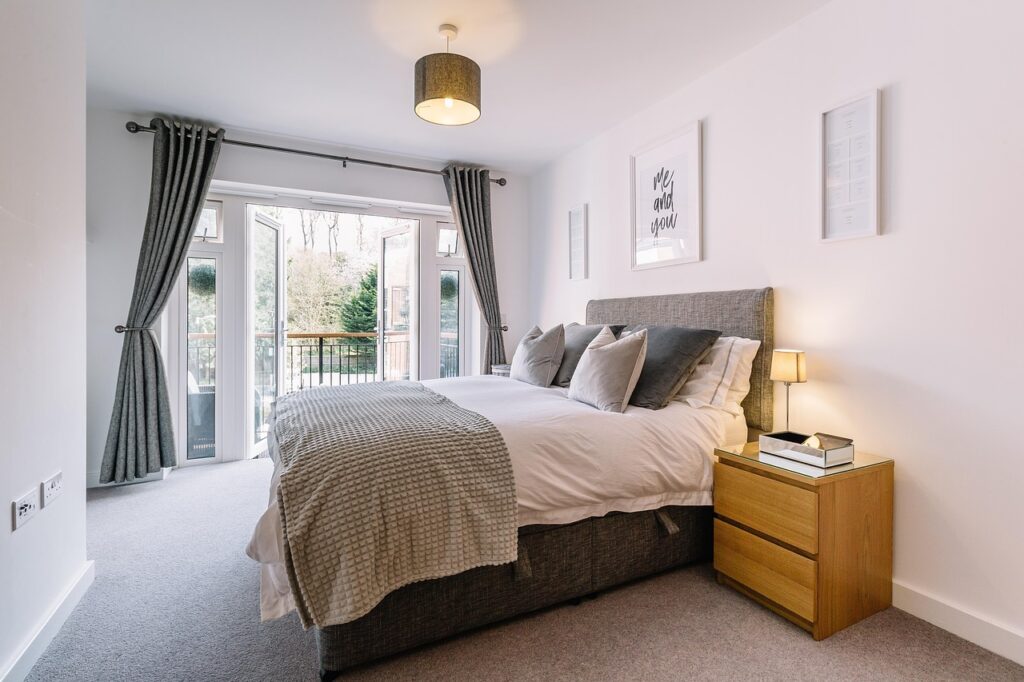 Newly added primary bedroom suite with private balcony access, modern décor, and soft natural lighting